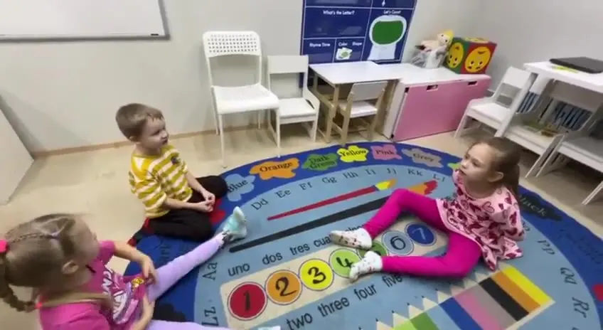 Дошкольники играют на ковре с карточками