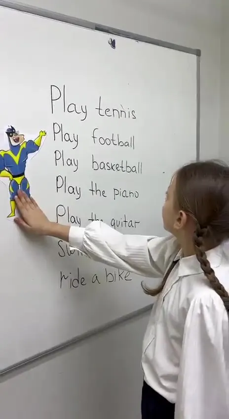 Ученица пишет на доске фразы Play tennis, Play football