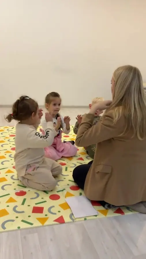 Педагог играет с малышами на мягком ковре